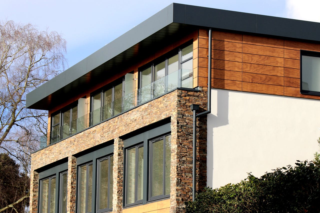 about-img Contemporary house in Poole featuring a striking mix of stone and wood facade with large windows.